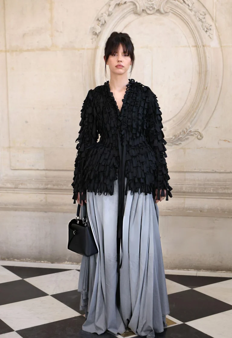 Mia Goth in a textured black Dior jacket and flowing gray trousers in Paris